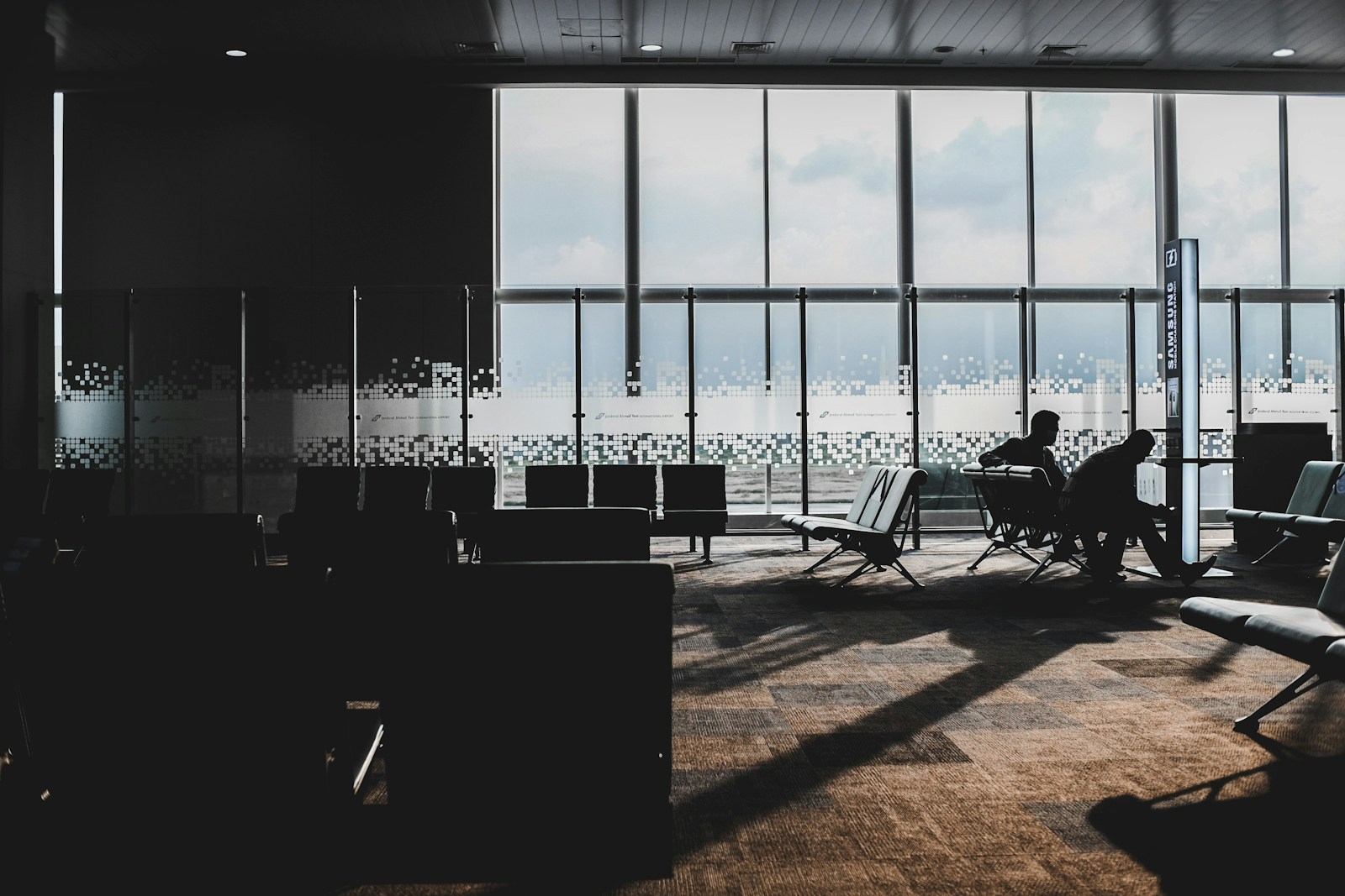 silhouette of people sitting on chair near body of water during daytime