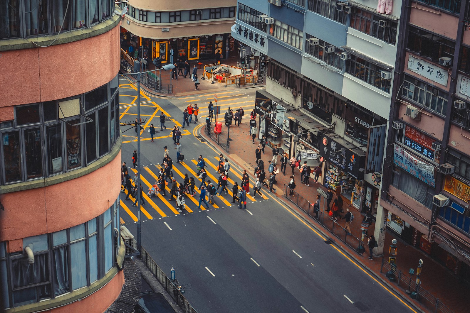 a group of people walking across a street next to tall buildings