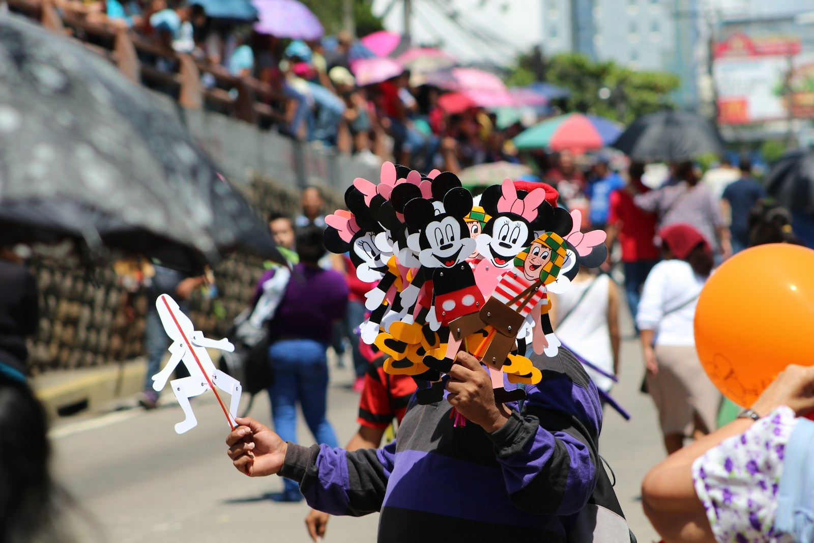 person in purple shirt holding mickey mouse balloon