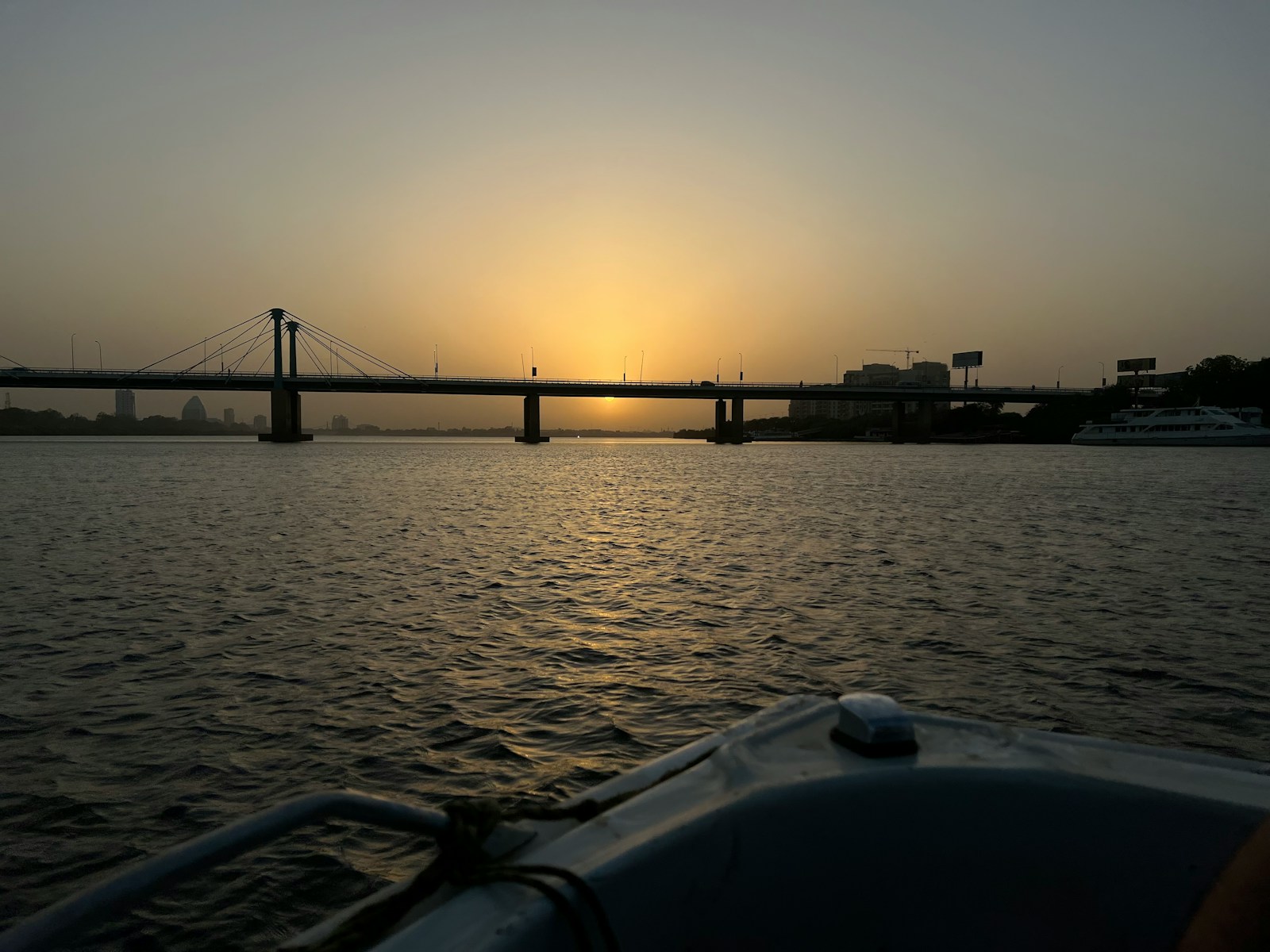 the sun is setting over a bridge over a body of water