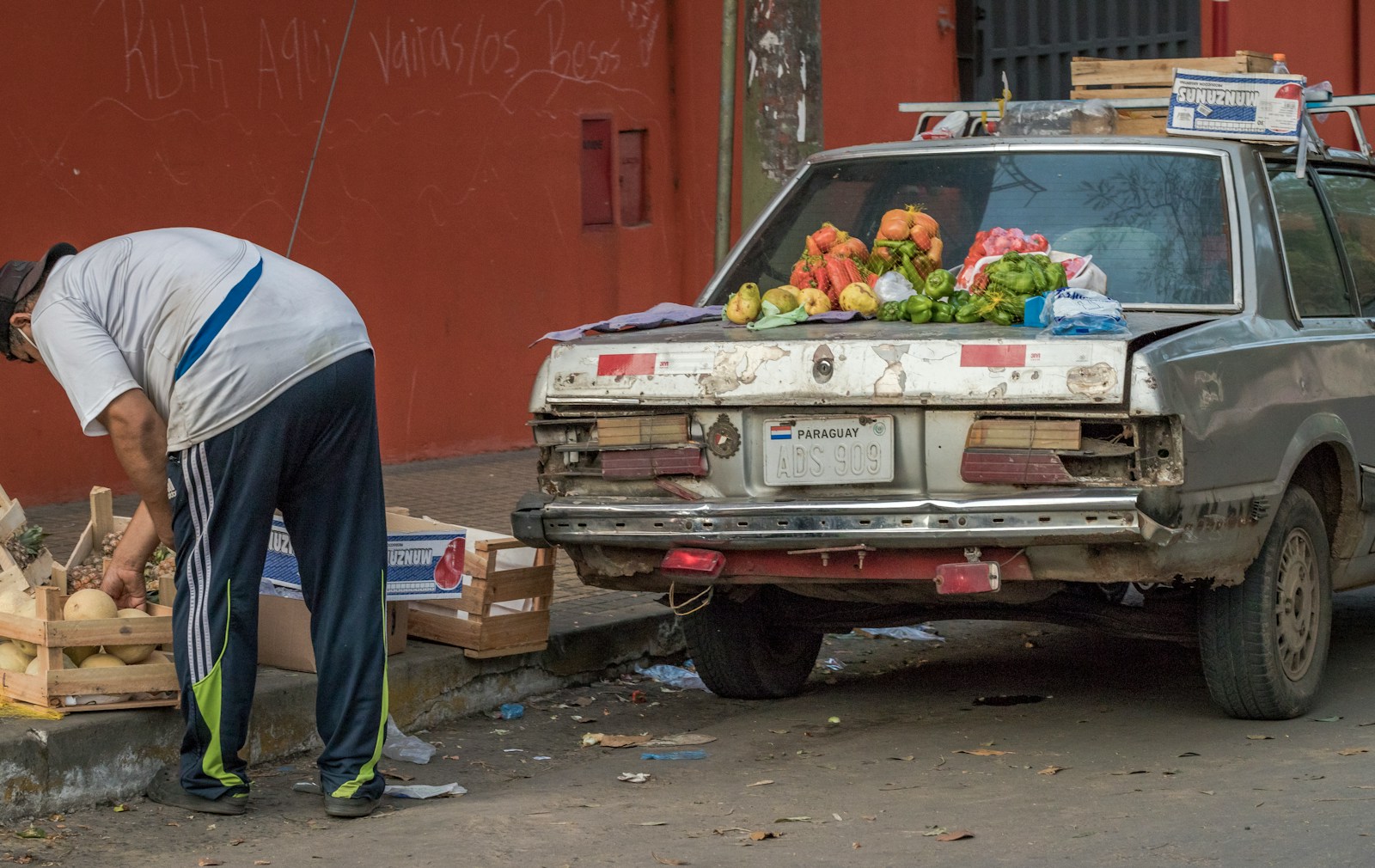 man in blue shirt standing beside red car