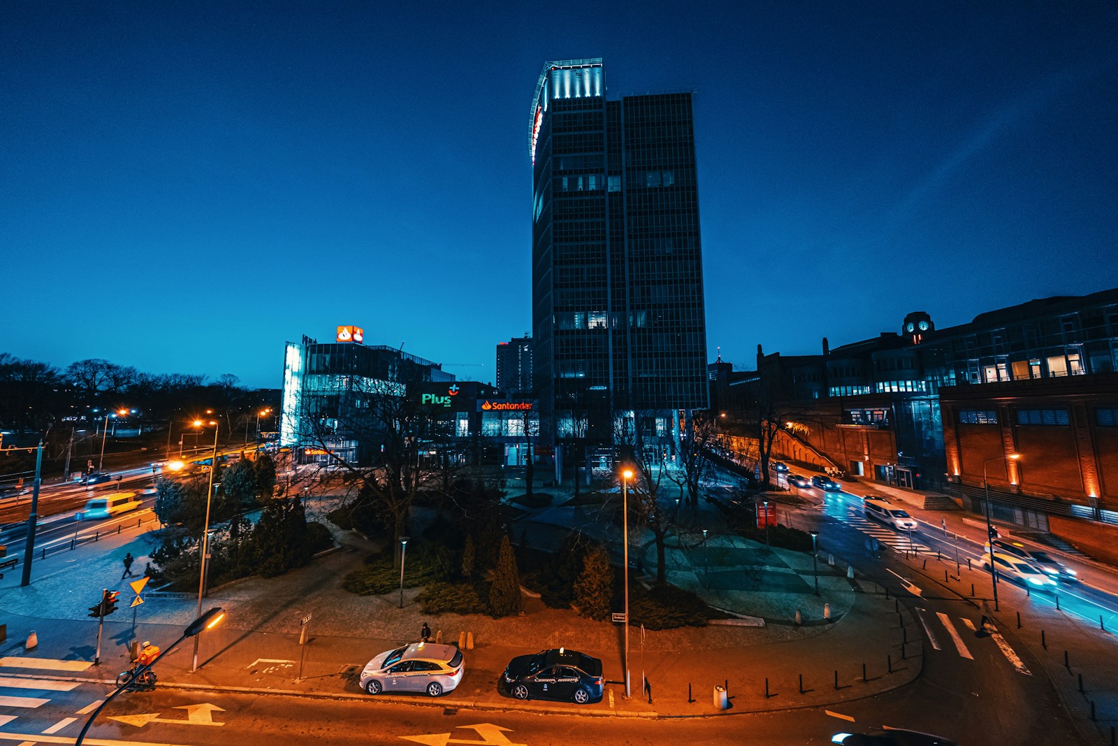 a city street at night with a tall building in the background