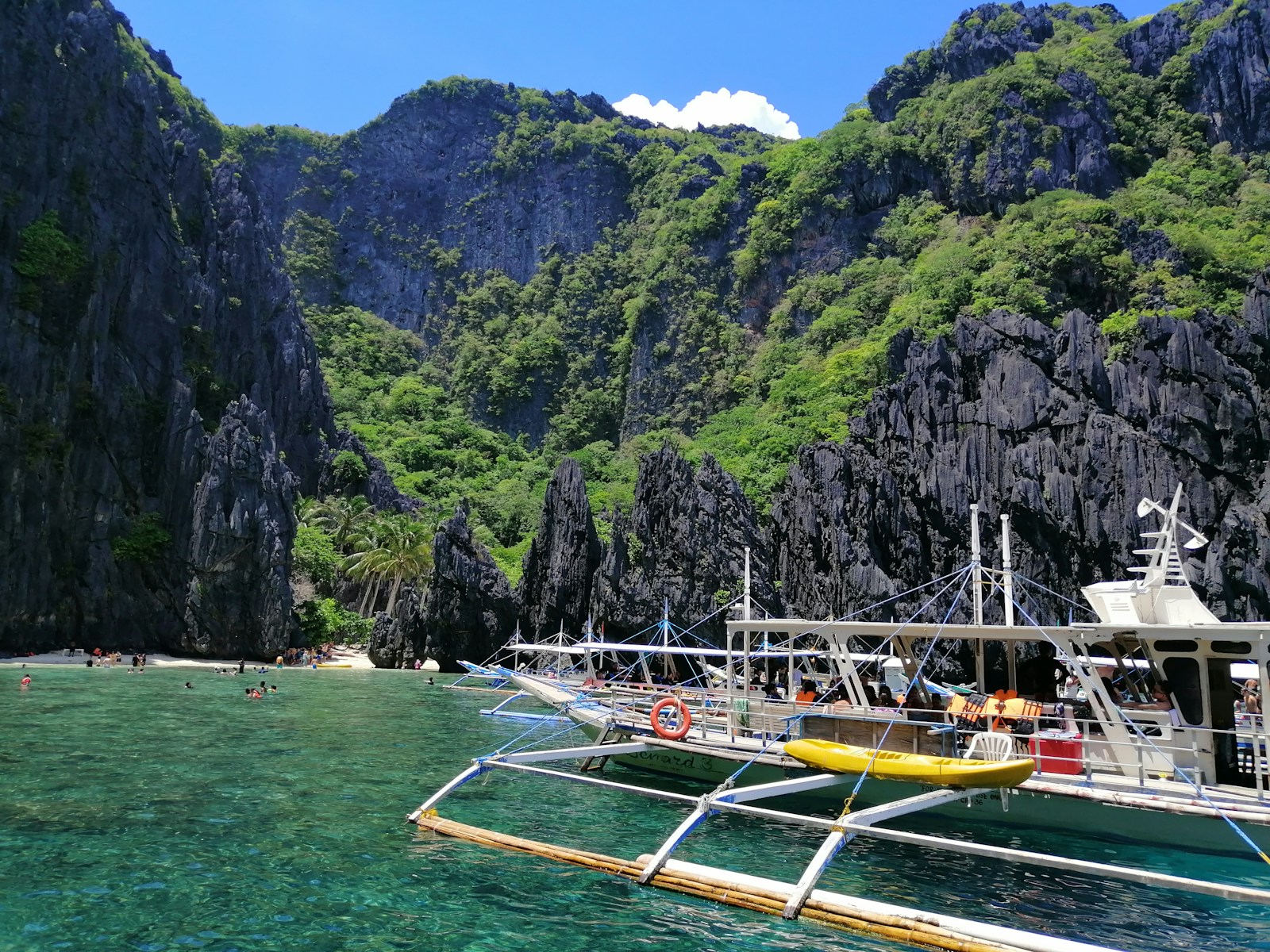 white and green boat on sea near mountain during daytime